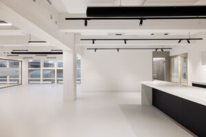 Moderne, minimalistische kantoorruimte aan de Generaal Vetterstraat met strakke witte muren, grote ramen en een lang zwart-wit keukenblad.